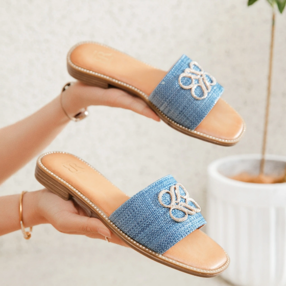 Mules plates en jean bleu avec un détail décoratif