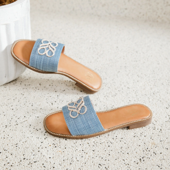Mules plates en jean bleu avec un détail décoratif